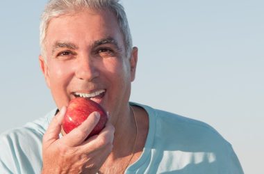 elderly man eating apple