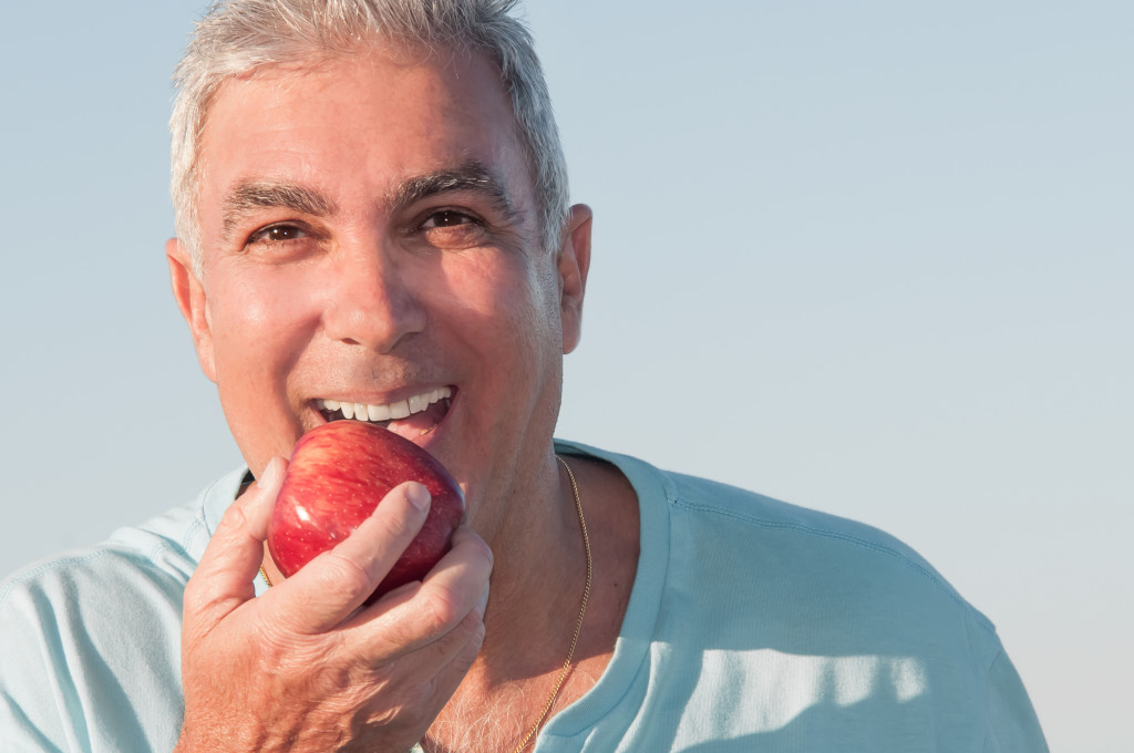 elderly man eating apple