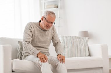 male senior on the couch feeling knee pain