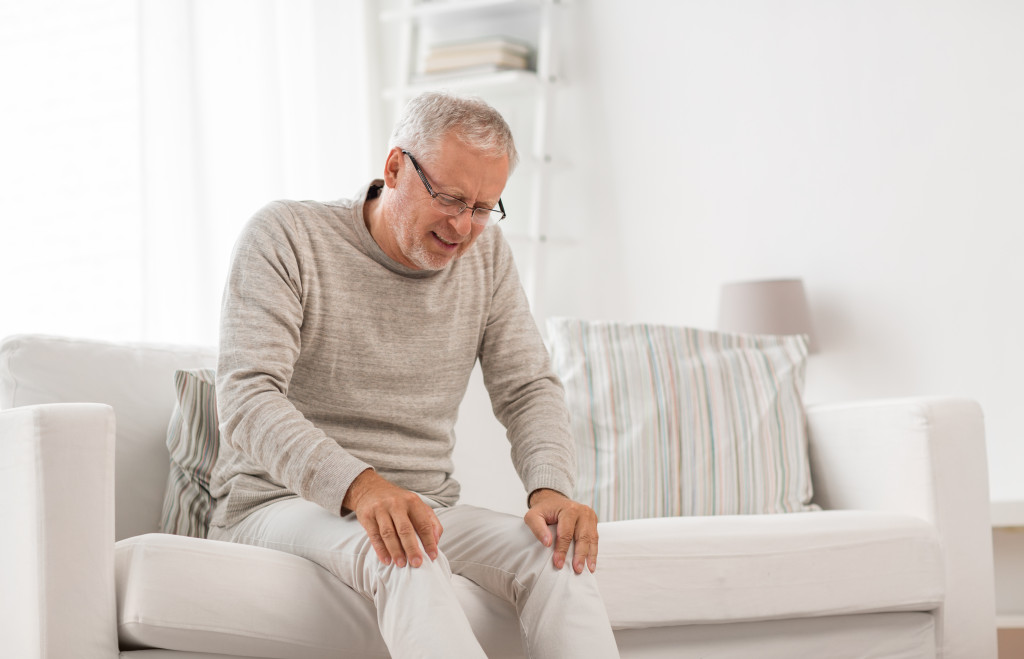 male senior on the couch feeling knee pain