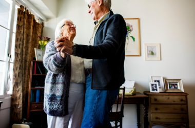 2 elderly man and woman dancing in an assisted living room